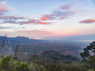 The view during a morning hike or sunrise on Mount Penanggungan is beautiful. It offers a vast landscape, including savannahs and ancient buildings like temples.
