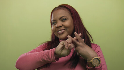 Woman wearing pink turtleneck and wooden watch making hashtag gesture with hands in studio; connection joy.