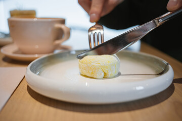 Close-up of a man sitting at a cafe table, enjoying a delicious mango and passion fruit mochi dessert.