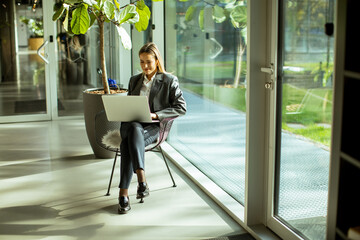 Professional woman working on laptop in modern office with natural light