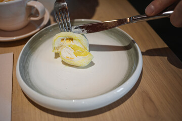 Close-up of a man sitting at a cafe table enjoying a delicious mango and passion fruit mochi dessert.
