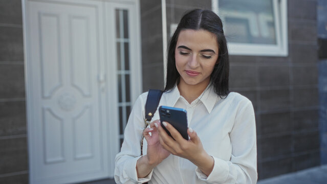 Young hispanic woman using smartphone on urban street in daylight showcasing modern technology and outdoor lifestyle, emphasizing communication and youth in city environment. - Powered by Adobe