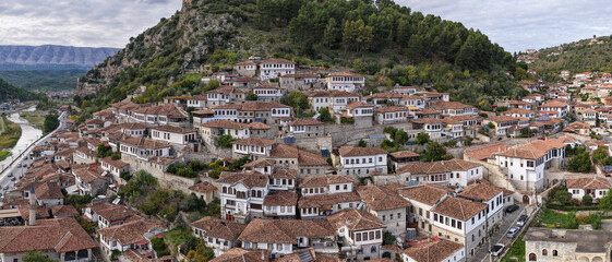 Panoramic view of Berat&rsquo;s hillside homes rising above the Osum River, framed by rocky cliffs and distant mountain ridges.