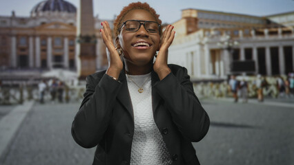 Young african american woman wearing glasses frames face with hands in vatican building; serenity...