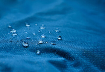 Water drops on waterproof membrane fabric. Detail view of texture of blue waterproof cloth.