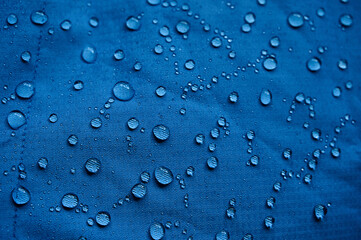 Water drops on waterproof membrane fabric. Detail view of texture of blue waterproof cloth.