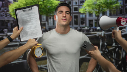 Man surrounded by hands holding megaphone, clipboard, alarm clock and smartphone on an amsterdam street; stress urgency.