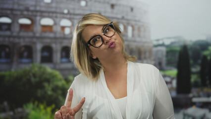 Young blonde woman puckering lips and wearing glasses in front of roman building outdoors;...