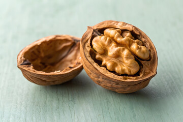 Ultra-detailed close-up of a split walnut shell featuring a conceptual inner engraving and rugged organic shapes on a smooth pastel sage surface.