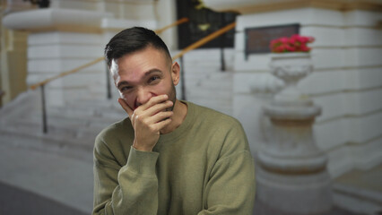 Young man laughing outdoors in an urban city setting, wearing casual clothing and exhibiting joyful...