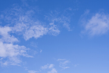 Bright blue sky with soft white clouds forming a gentle natural background. Minimal and calm atmosphere suitable for weather themes, nature concepts, clean backdrops and peaceful outdoor scenes.
