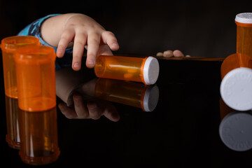 A powerful conceptual photograph showing a child's hand reaching for colorful, unattended...