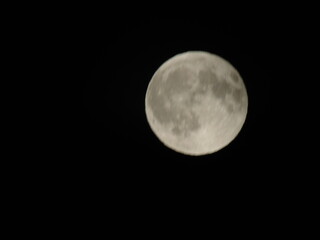 Genova, Italy - 07/09/2025: An amazing photography of the full moon over the city of Genova by night with a great clear and blue sky in the background and some stars.