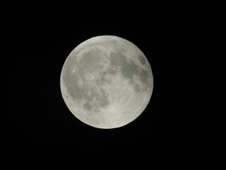 Genova, Italy - 07/09/2025: An amazing photography of the full moon over the city of Genova by night with a great clear and blue sky in the background and some stars.