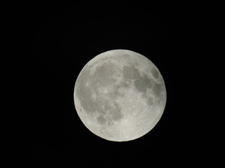 Genova, Italy - 07/09/2025: An amazing photography of the full moon over the city of Genova by night with a great clear and blue sky in the background and some stars.