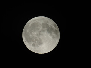 Genova, Italy - 07/09/2025: An amazing photography of the full moon over the city of Genova by night with a great clear and blue sky in the background and some stars.