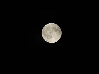 Genova, Italy - 07/09/2025: An amazing photography of the full moon over the city of Genova by night with a great clear and blue sky in the background and some stars.