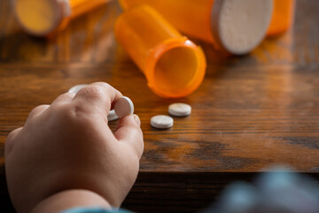 A powerful conceptual photograph showing a child's hand reaching for colorful, unattended...