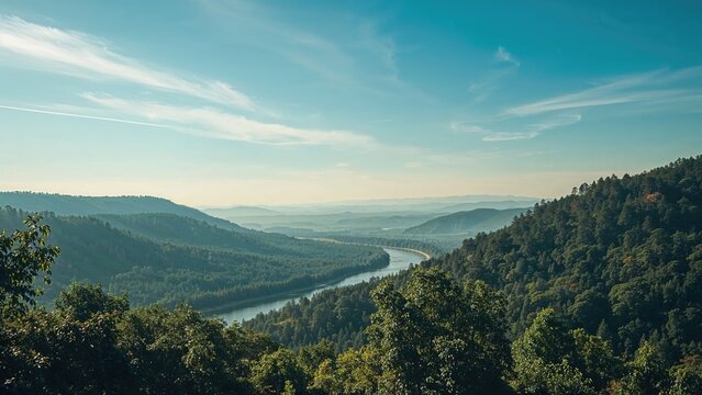 View of river in valley surrounded by green hills under blue sky