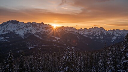 Sunset over snow-capped mountains and pine forest, with the sun just above the peaks, creating a warm glow in the sky.
