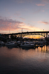 Fototapeta premium Vancouver, Canada – May 23, 2021 - Granville Bridge over False Creek Yacht Club.The Granville Bridge arches over False Creek at sunset. Boats tied up at the False Creek Yachtclub docks. 