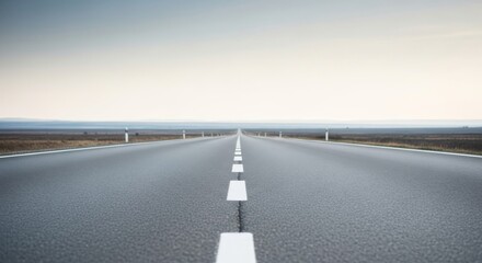 A long straight asphalt road with white dashed center lines stretching toward the distant horizon under a bright, neutral sky.