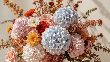 A bouquet of pastel and vibrant flowers, including hydrangeas, carnations, and daisies, arranged with greenery and dried accents.
