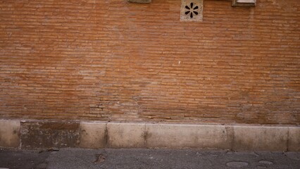 Weathered orange brick wall texture on street with visible mortar lines, chips and subtle stains, sharp surface detail; background backplate copyspace calm.