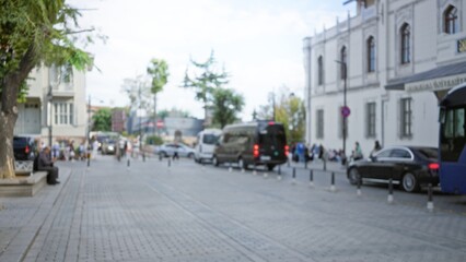 Obraz premium Soft defocused street with cobblestone pavement, parked cars and trees; background backplate copyspace overlay.