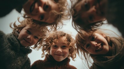 Group of joyful children huddling and smiling, looking down at camera from low angle, showing diverse friendship and cheerful togetherness