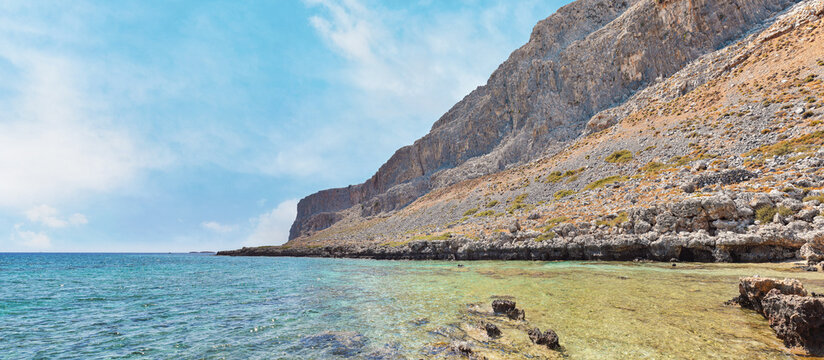 Panorama of rocky shore at Navarone Bay, Rhodes, calm clear sea near