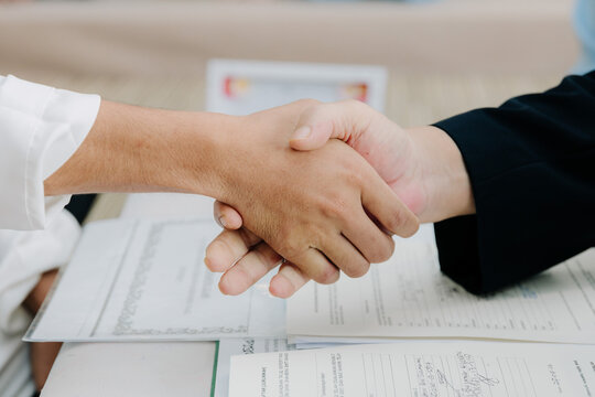 A formal handshake between two men over Islamic marriage contract documents during a Nikah ceremony