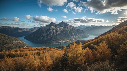 Obraz premium Landscape of mountains, lake, and autumn trees under a partly cloudy sky. Nature scenery with vibrant fall foliage and distant peaks.