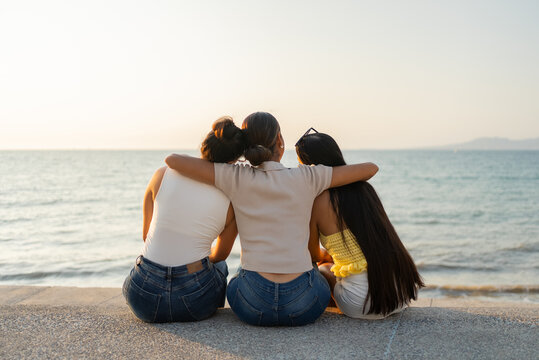 Three young women embracing enjoying sunset at beach in puerto vallarta