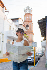 Young woman exploring Puerto Vallarta with a map, iconic church in the background