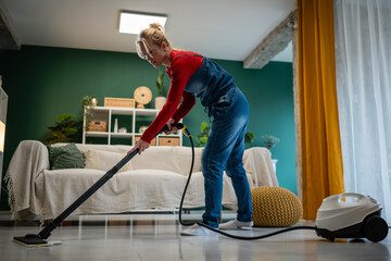 Woman cleaning living room floor with steam cleaner