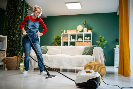 Woman feeling tired cleaning floor with steam cleaner
