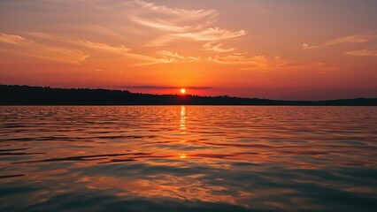 Fototapeta premium Sunset over a body of water with orange and pink hues in the sky. Peaceful and scenic landscape at dusk.