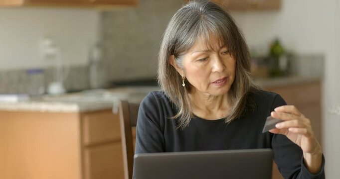Freelance mature woman shopping online using credit card and online laptop computer at home - Powered by Adobe