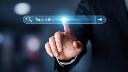 Man's hand touching a glowing search bar on a dark background finger pressing