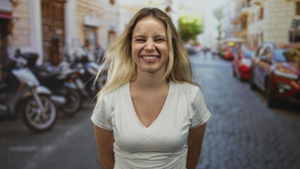 Fototapeta premium Woman laughing with head tilted, white t shirt and visible chest on sunlit cobbled street; carefree joy.