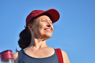 retrato de mulher madura, rosto com rugas de frente ao sol, iluminada e satisfeita com sua...