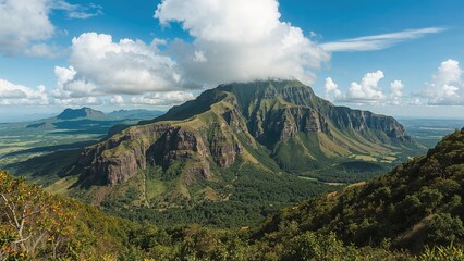 Vast mountain landscape with lush greenery, dramatic cliffs, and a partly cloudy sky.