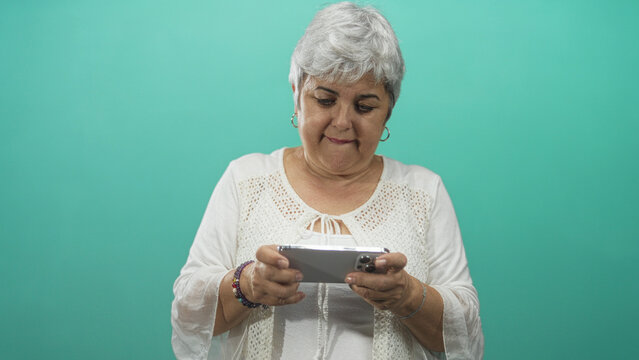 Woman holding smartphone with both hands looking down and tapping screen in studio; concentration learning. - Powered by Adobe