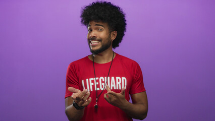 Lifeguard man smiling and gesturing against a vivid purple background in a studio setting,...