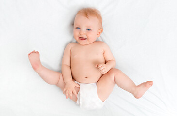 A happy ten-month-old baby lies playfully on a light background