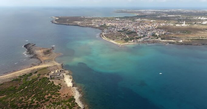 Aerial view of the isthmus of sea separating the coastal village of Portopalo from the island of Capo Passero. This tourist destination is located at the southern tip of Sicily, Italy.