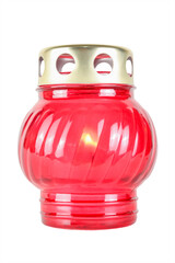 A memorial candle burning in a red glass lamp