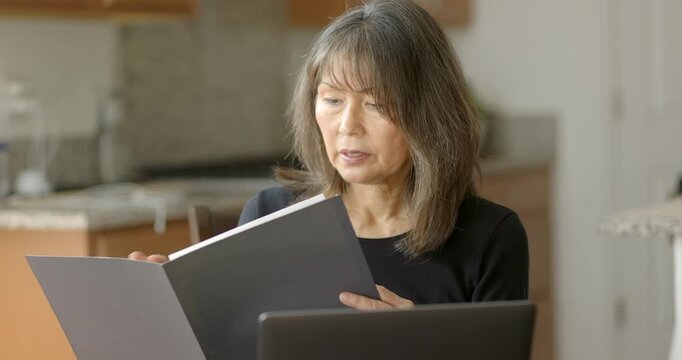Professional mature woman reading business folder communication at laptop computer