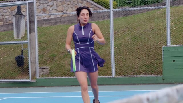 Latina beginner tennis player hitting low backhand during practice